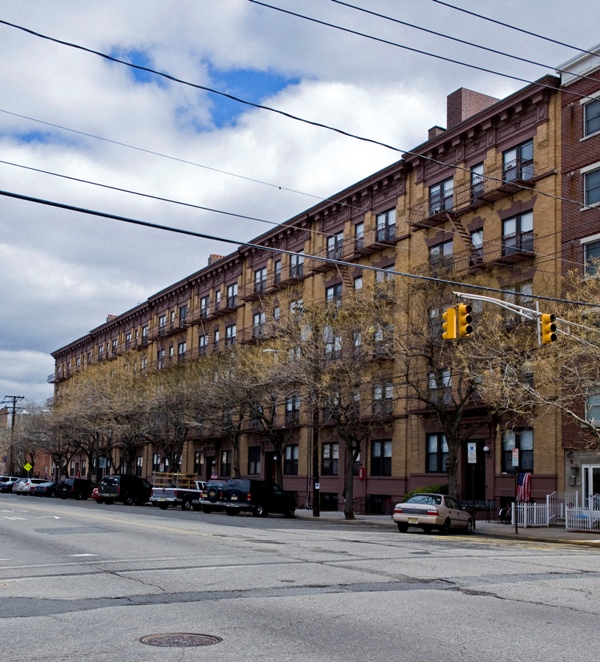 A street view of a residential building with cars parked on the side.