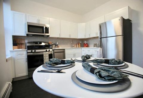 A kitchen with a white table and black plates.