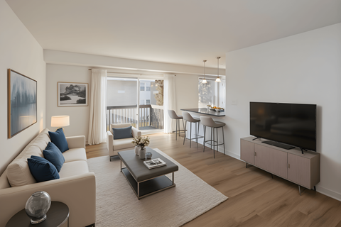 A living room with a white couch, a coffee table, and a television.