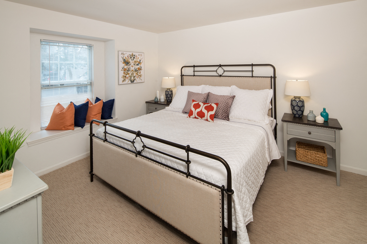 A bedroom with a large bed and a nightstand with a lamp.