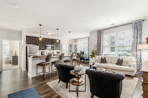 A modern living room with a kitchen in the background.