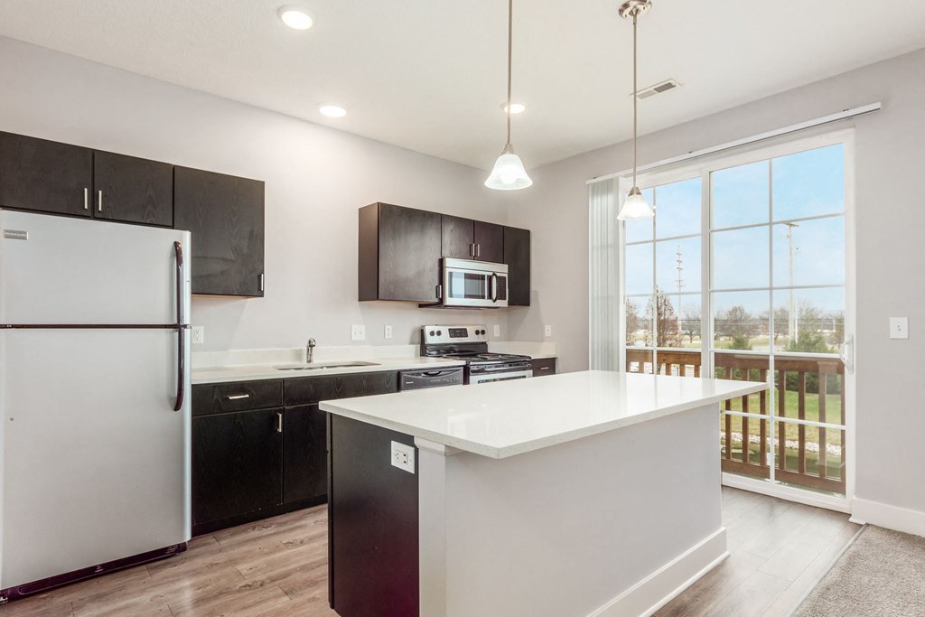 A modern kitchen with a white island and black cabinets.