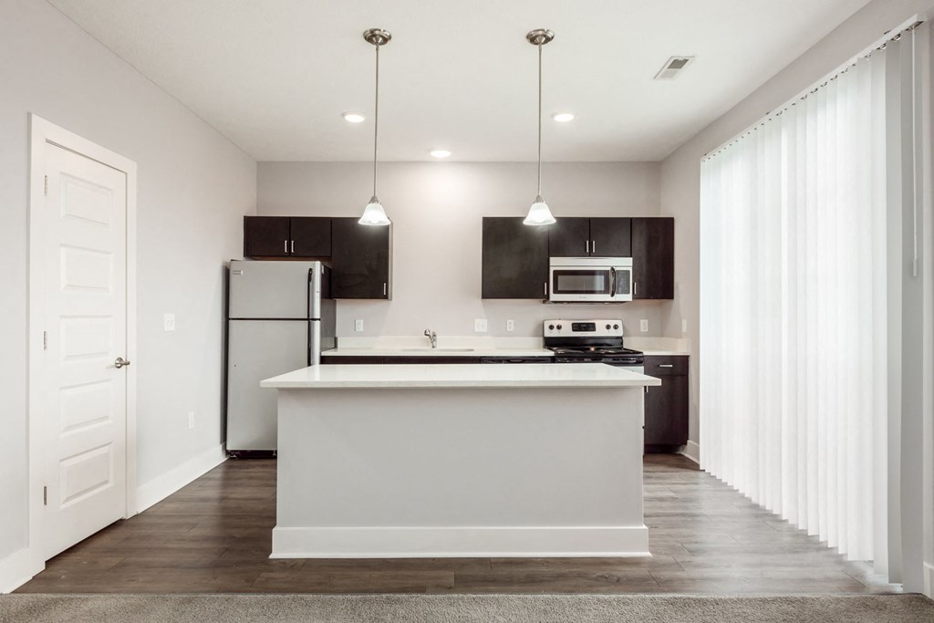 A modern kitchen with a white island and dark brown cabinets.