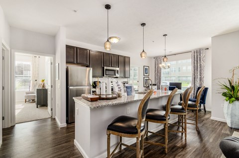 A kitchen with a white island and black chairs.