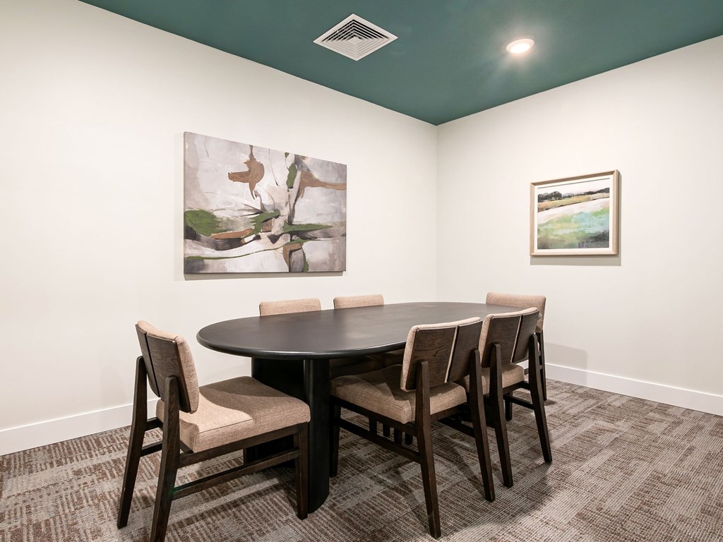 A conference room with a table and chairs and two pictures on the wall.