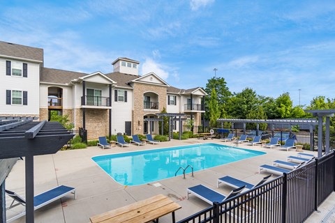 A swimming pool area with sun loungers and a building in the background.