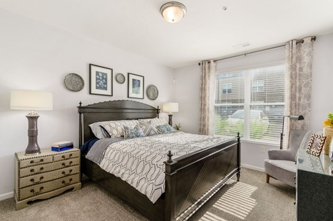 A bedroom with a large bed, a nightstand, and a chair.