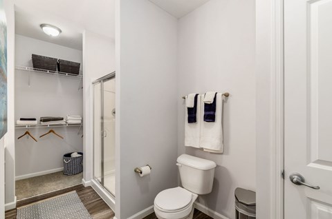 A white bathroom with a toilet, towel rack, and a mirror.