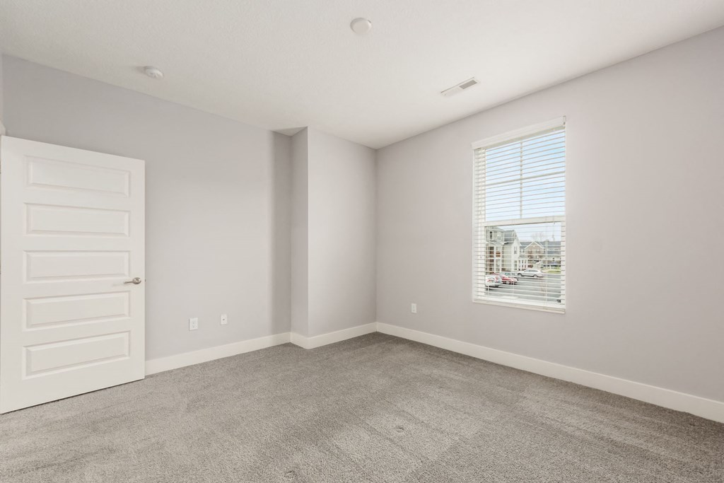 A room with a white door and a window with blinds.