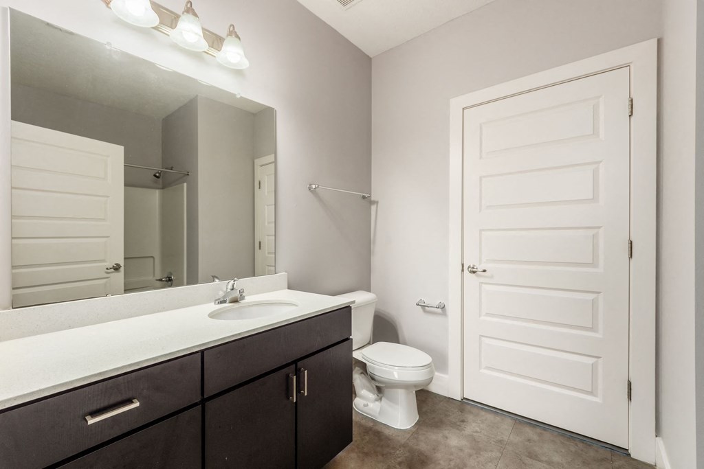 A white toilet sits in a bathroom with a white sink and a white door.