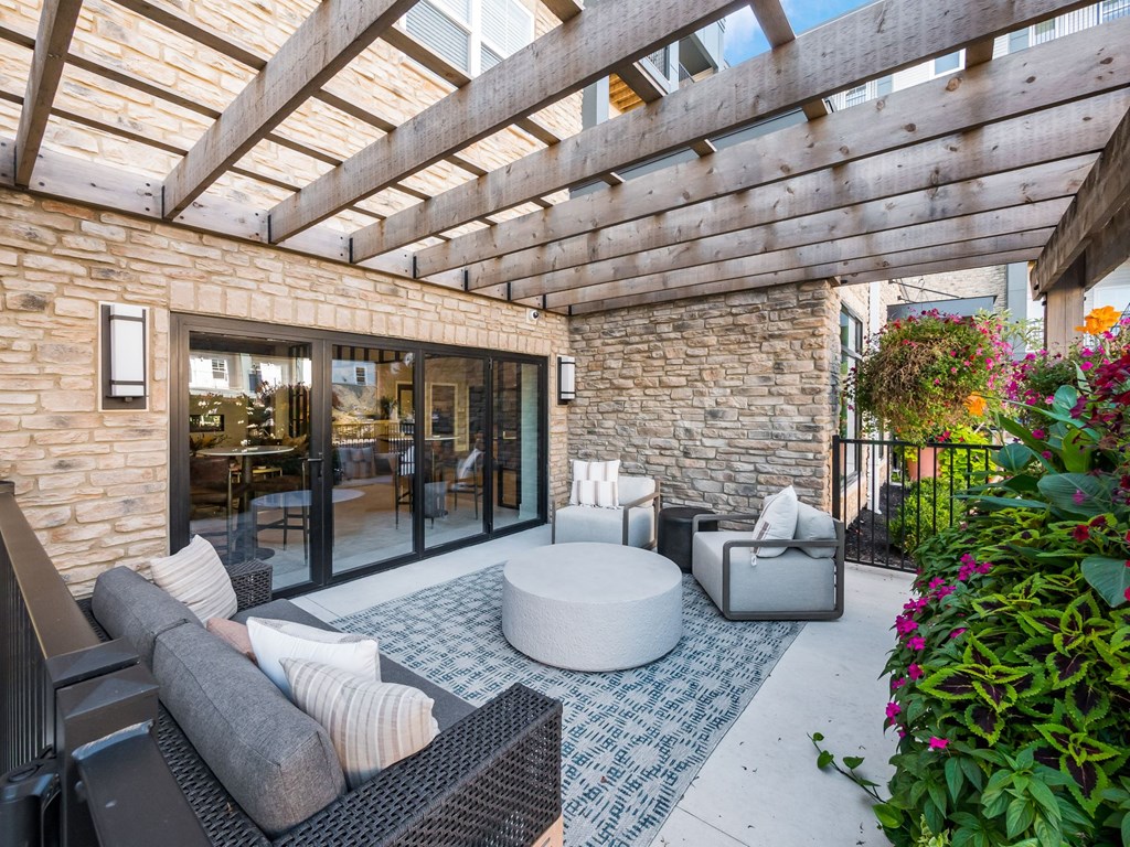A patio with a black sofa, a round table and a stone wall.