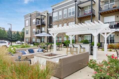 A patio with a white pergola and a planter box is surrounded by apartment buildings.