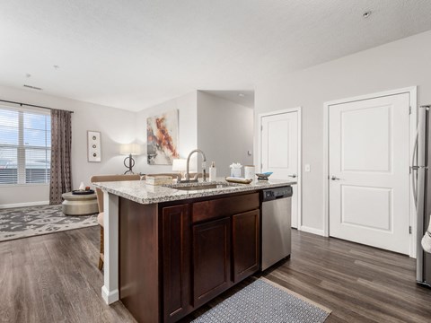a kitchen with an island and a living room with a refrigerator and sink