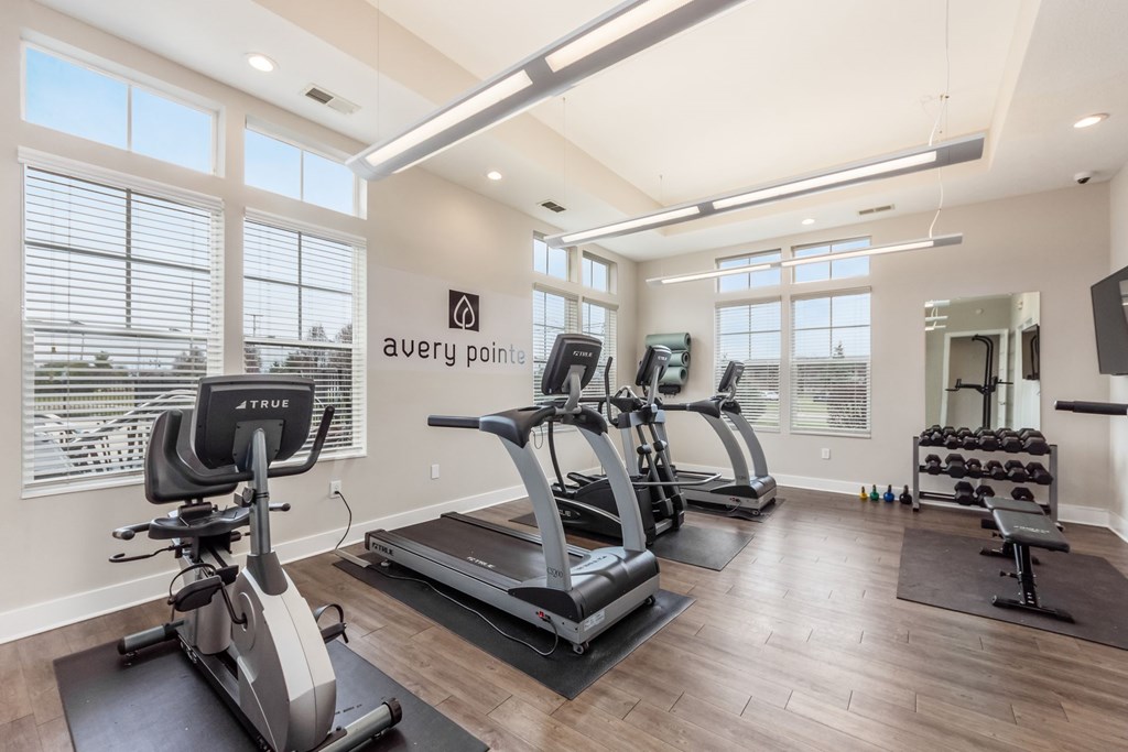 Avery Point fitness room with treadmills, elliptical machines, and dumbbells.