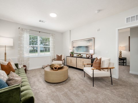 A living room with a green couch, a coffee table, and a painting on the wall.