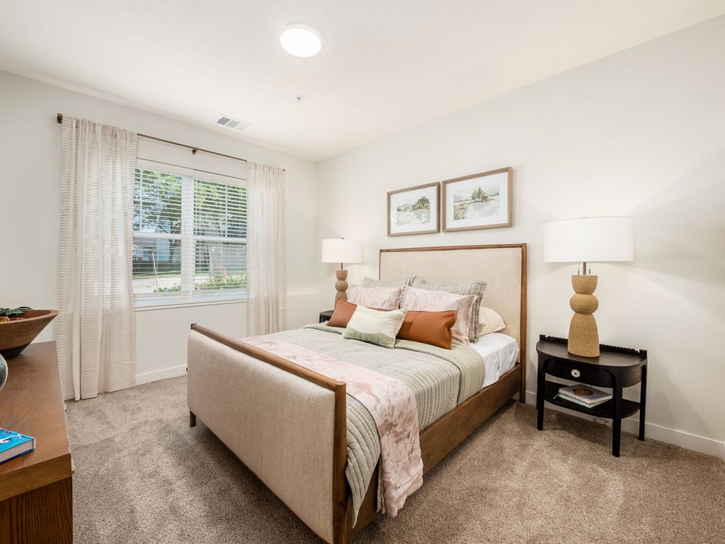 A bedroom with a large bed and a nightstand with a lamp on it.