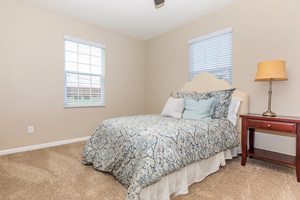 A bedroom with a bed, nightstand, and window.