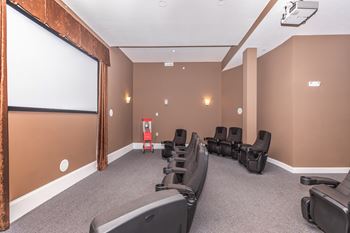 A row of black chairs are lined up in front of a screen in a room.