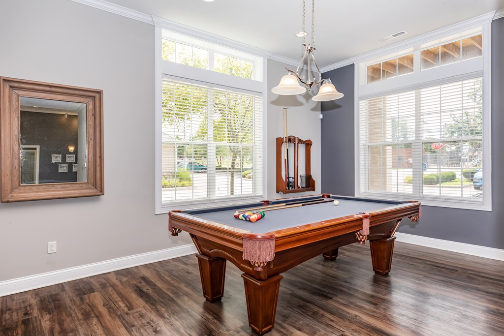A pool table in a room with a mirror and a picture frame on the wall.