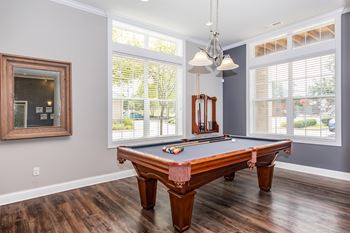 A pool table in a room with a mirror and a picture frame on the wall.