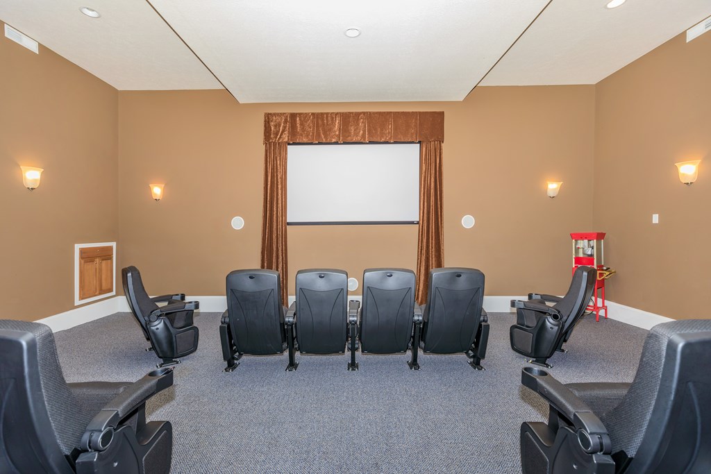 A conference room with a white screen and black chairs.