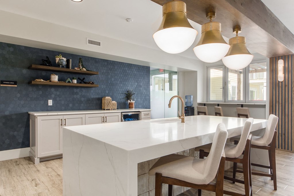 a kitchen with a marble counter top and white chairs