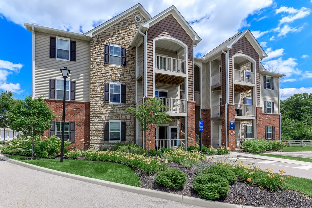 A large apartment complex with multiple balconies and a well-maintained garden in front.