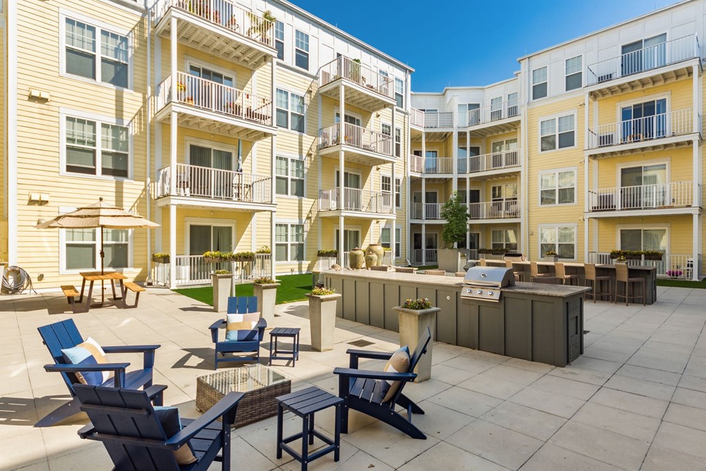a patio with chairs and tables in front of an apartment building