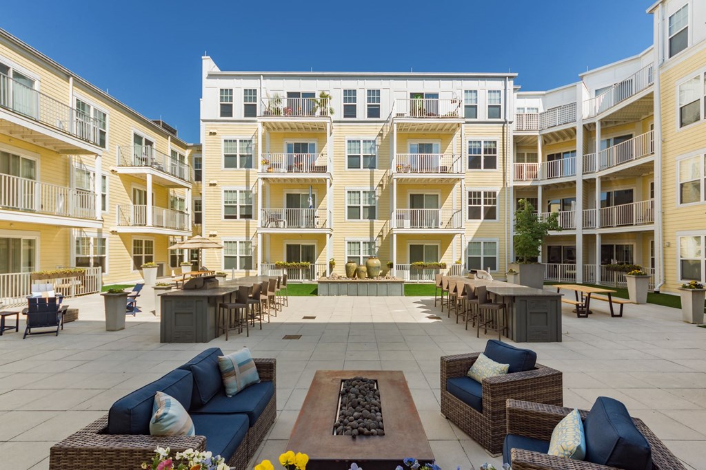 an open courtyard with furniture and tables in front of an apartment building