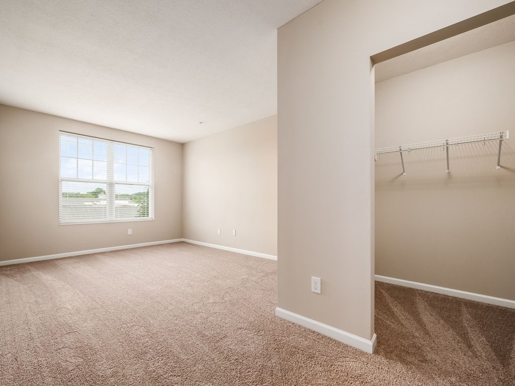 an empty bedroom with a closet and a window