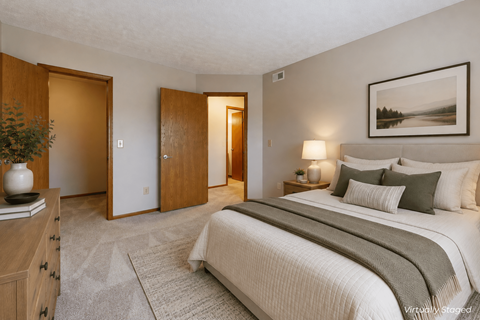 A bedroom with a large bed and a painting on the wall.