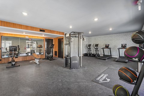 A gym with a variety of equipment including treadmills, weights, and exercise machines.