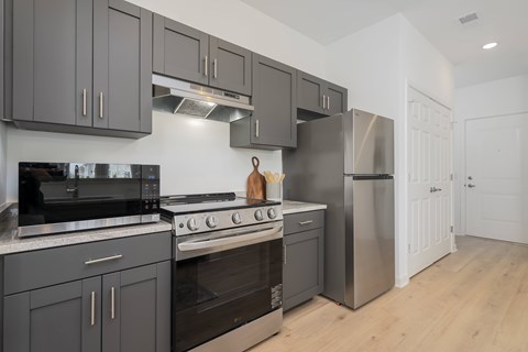 A modern kitchen with dark grey cabinets and stainless steel appliances.