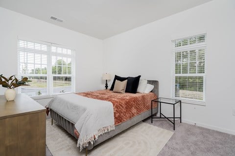 A bedroom with a bed, nightstand, and window.