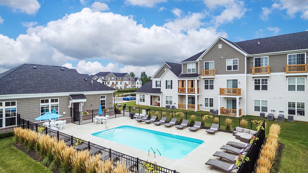 a swimming pool with lounge chairs in front of apartment buildings