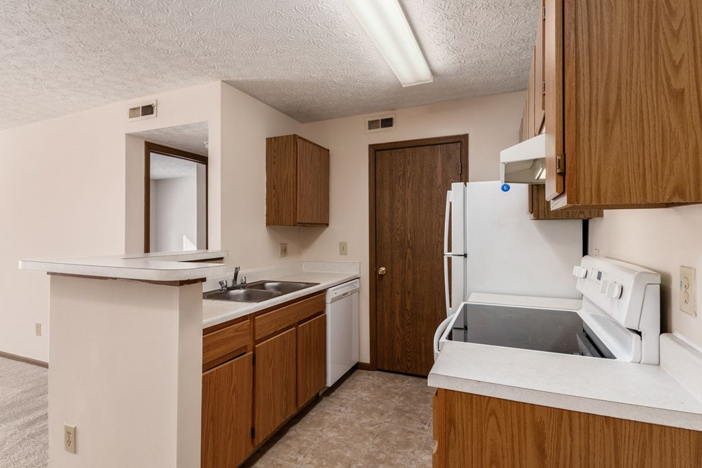an empty kitchen with white appliances and wooden cabinets