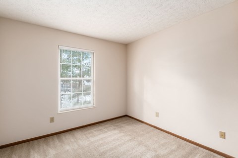 a bedroom with white walls and a window