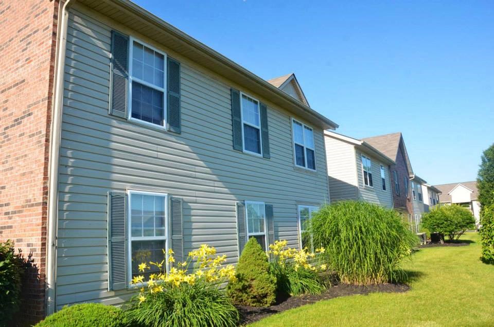 the side of a house with a yard and flowers