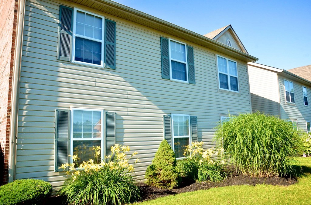 the side of a blue house with a lawn and plants
