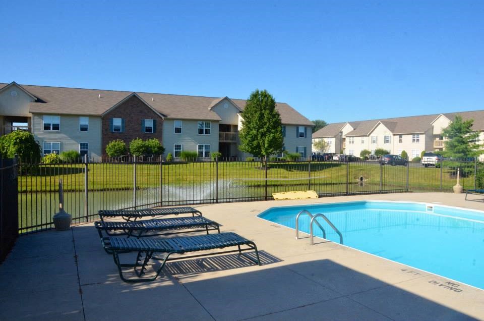 a swimming pool with benches in front of an apartment building