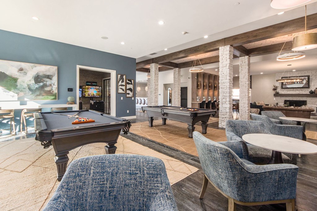 a game room with two pool tables and chairs