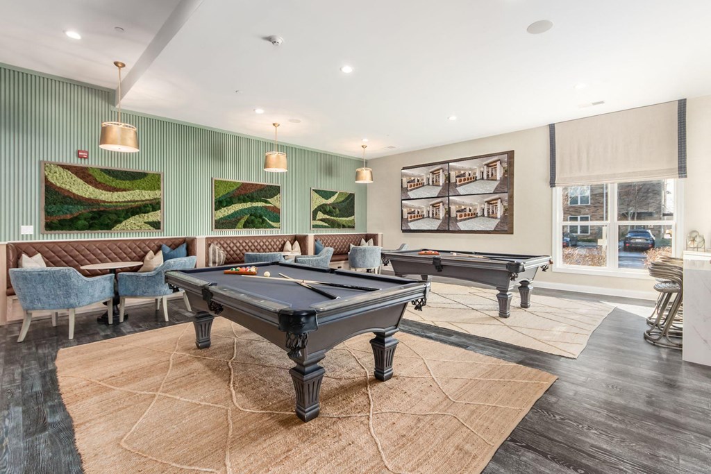 a game room with two pool tables and chairs
