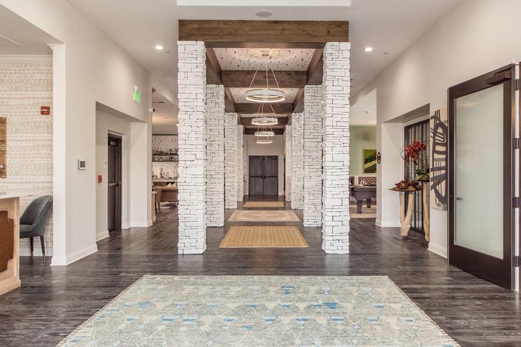 the lobby of a building with a long hallway with stone columns