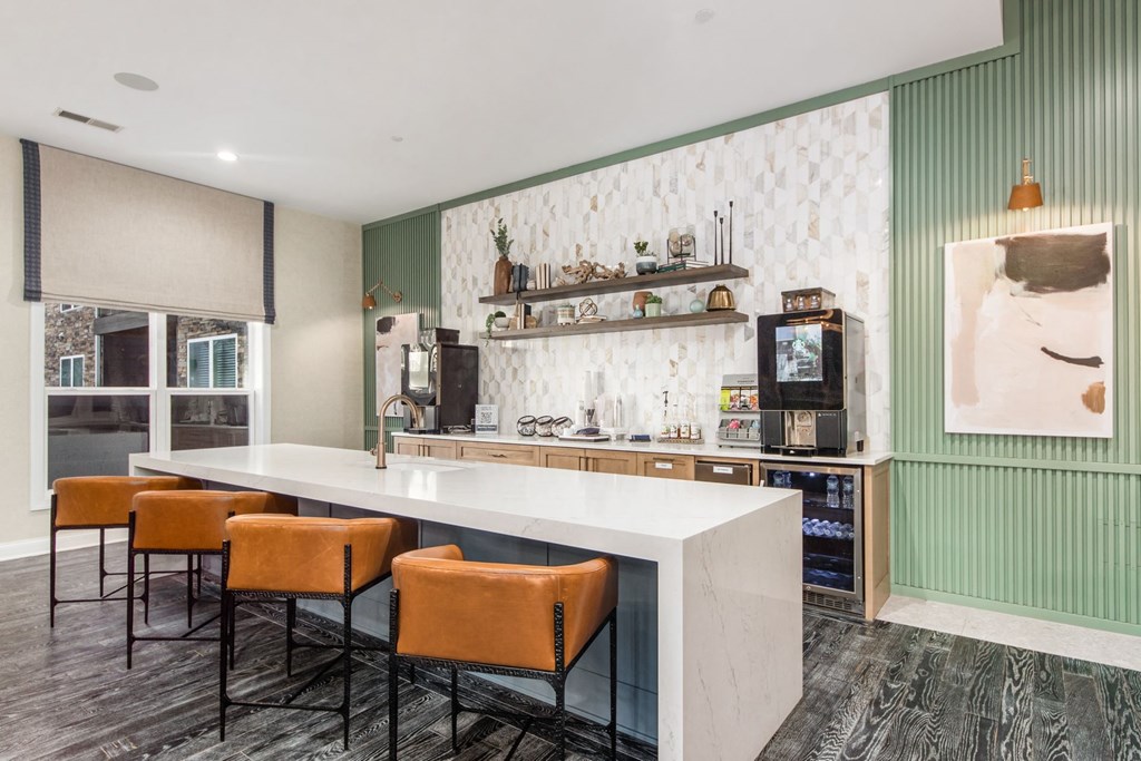 a kitchen with a long white counter and orange chairs