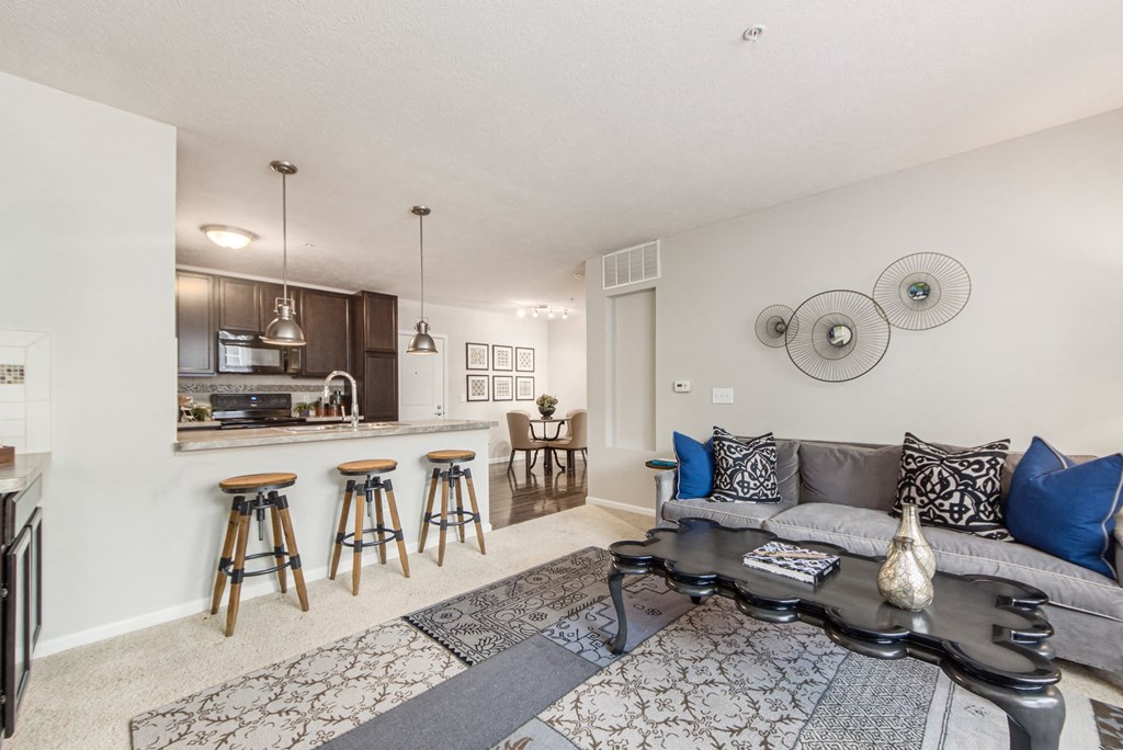 a living room with a couch and a bar with stools