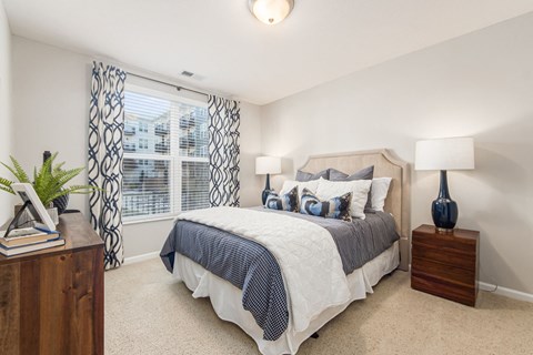 A bedroom with a bed, nightstands, and a window with curtains.