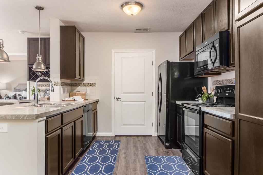 an open kitchen with black appliances and wood cabinets