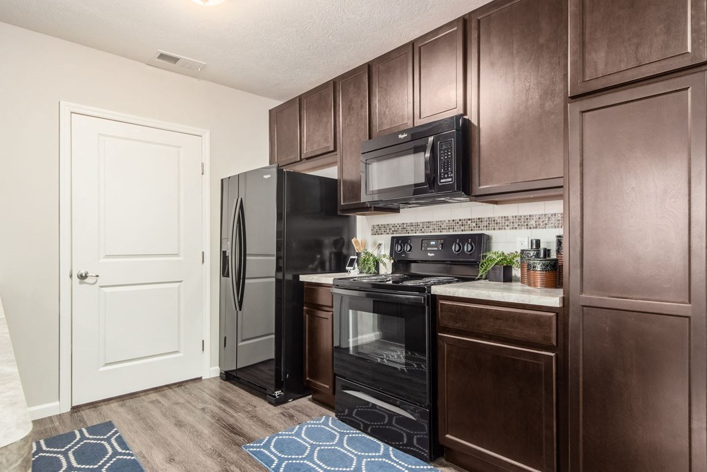 our apartments offer a kitchen with black appliances and wood cabinets