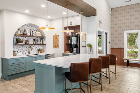 a kitchen with a large white counter top and chairs