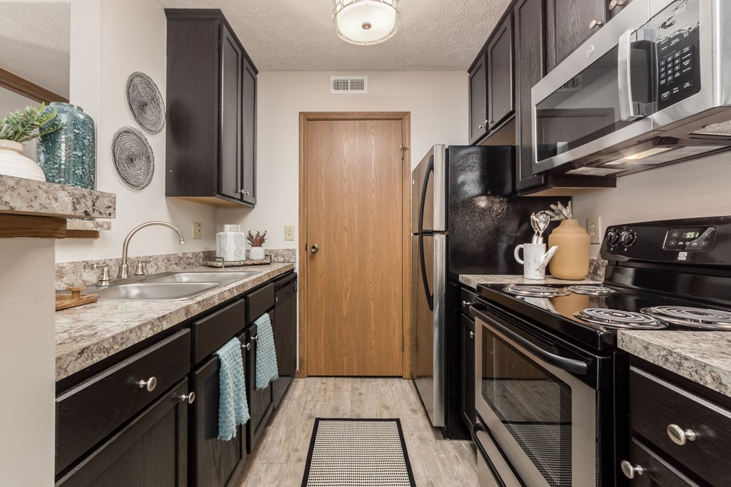 a kitchen with black appliances and granite counter tops and a door to a refrigerator